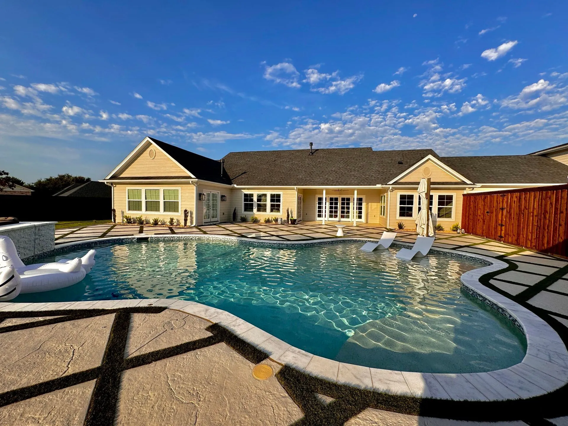 Custom freeform pool with chaise loungers at a North Texas home