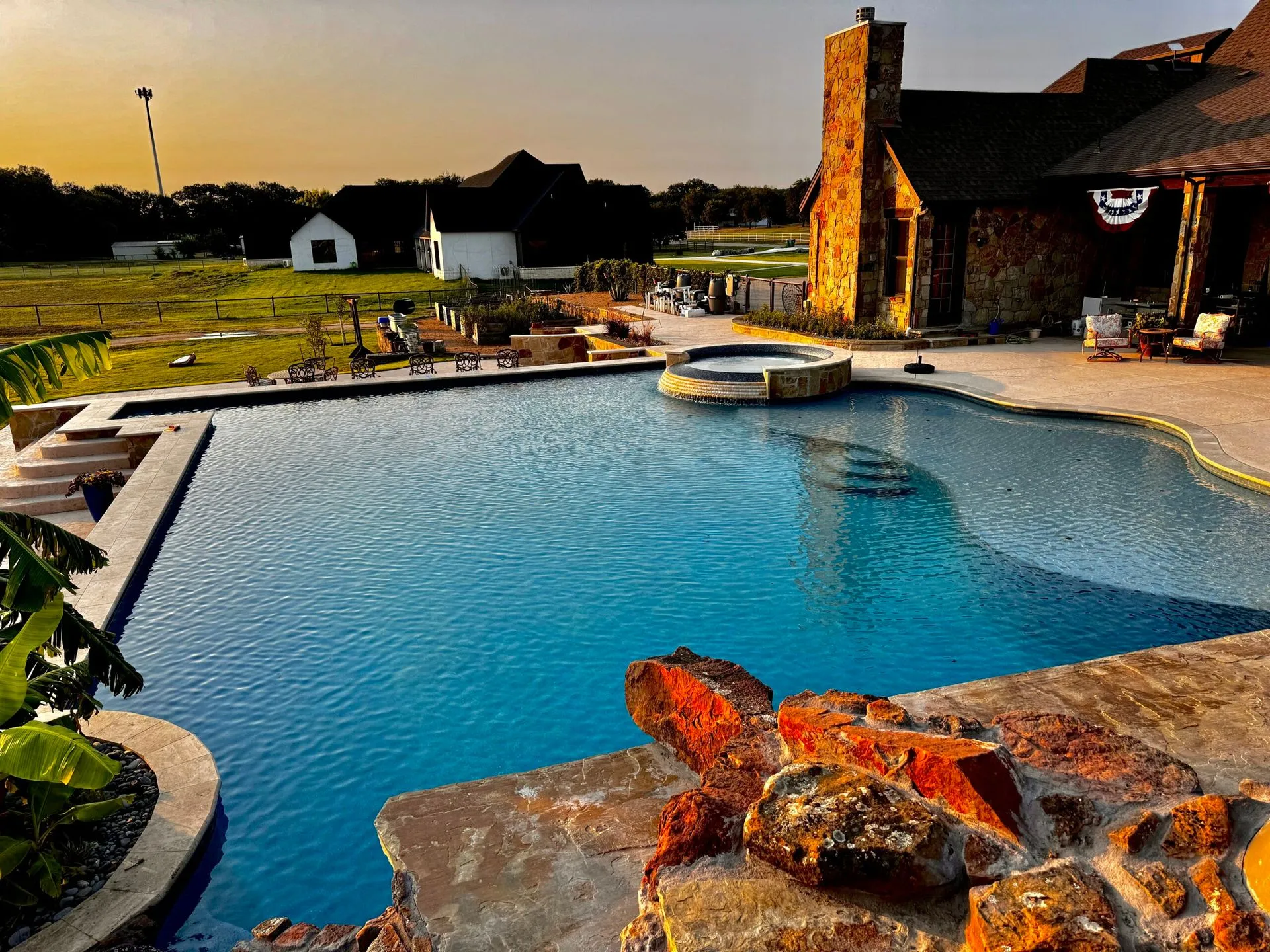 Freeform lagoon pool with rock grotto, slide, and tropical landscaping